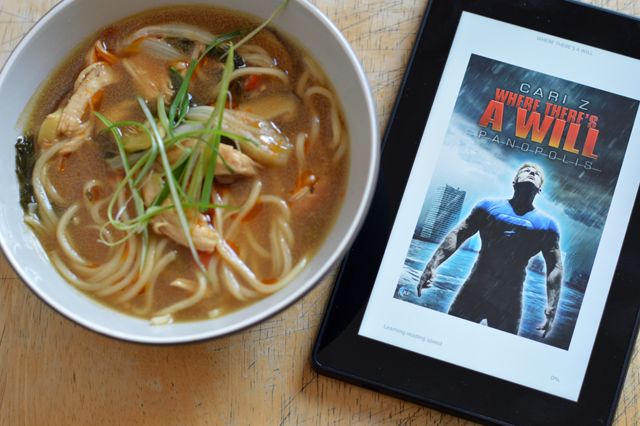 A Bowl of spicy chicken soup with a Kindle. The cover on the screen is Where There's A Will by Cari Z.